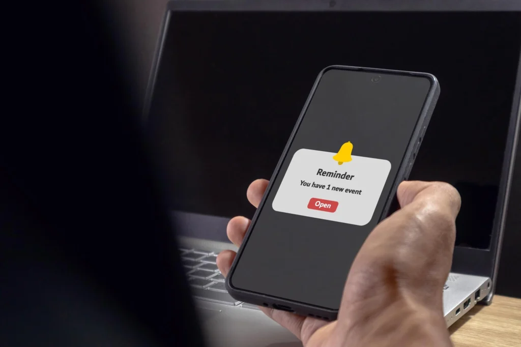 Man smiling while checking a phone notification, illustrating Shifton’s Instant Alerts feature for real-time updates and communication.