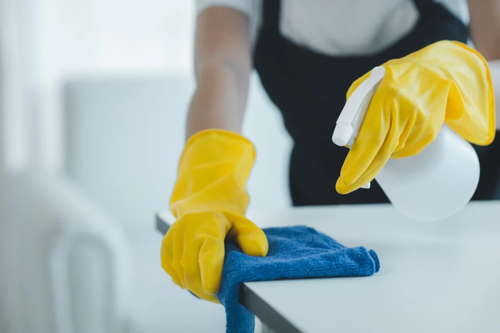 Professional cleaner mopping a living room floor with cleaning equipment and supplies nearby.