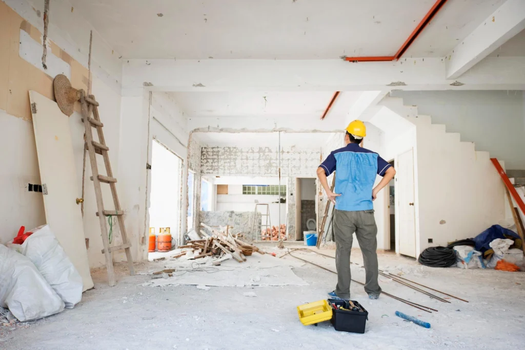 Contractor holding a power drill while working on interior home renovation with unfinished walls.