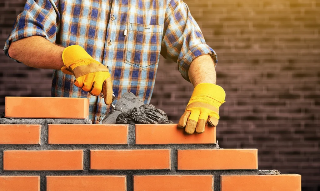 Construction workers building a concrete and masonry wall on-site — field service project management