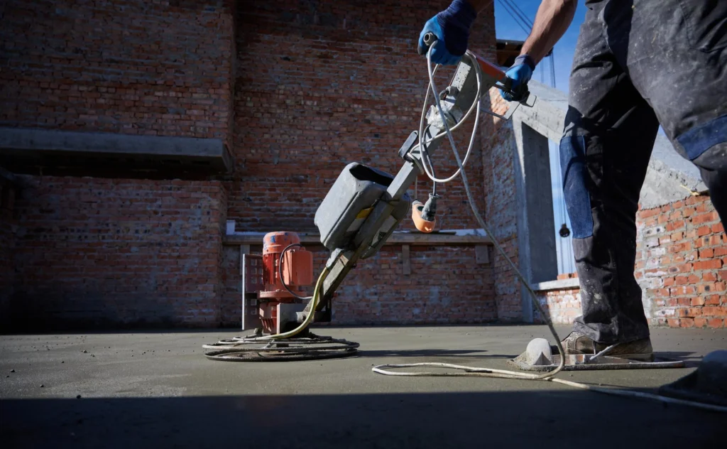 Construction worker leveling floor screed with a trowel on a building site